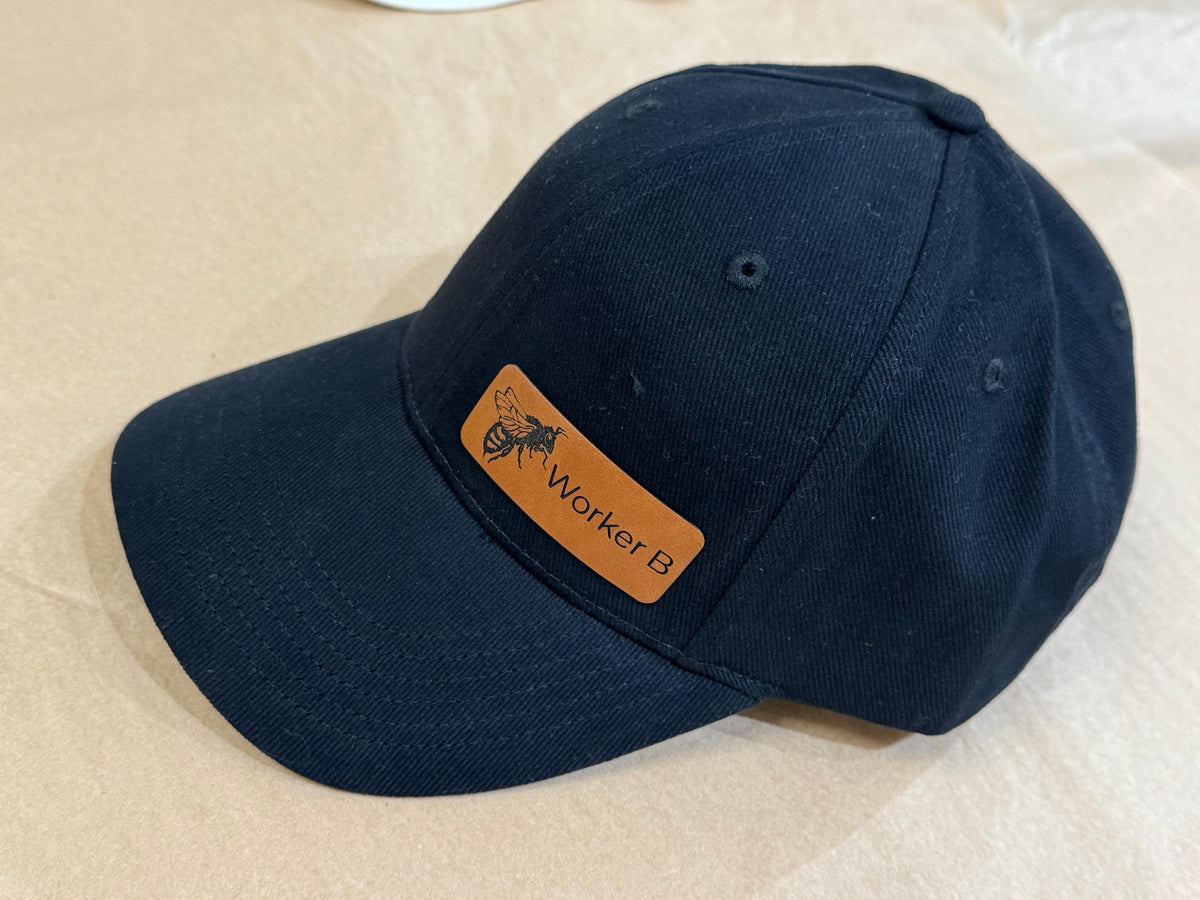 Black Baseball cap with a brown leather patch on a beige surface