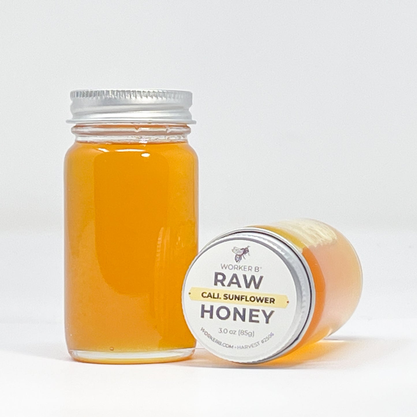 Jar of raw sunflower honey with a white label on a light gray background