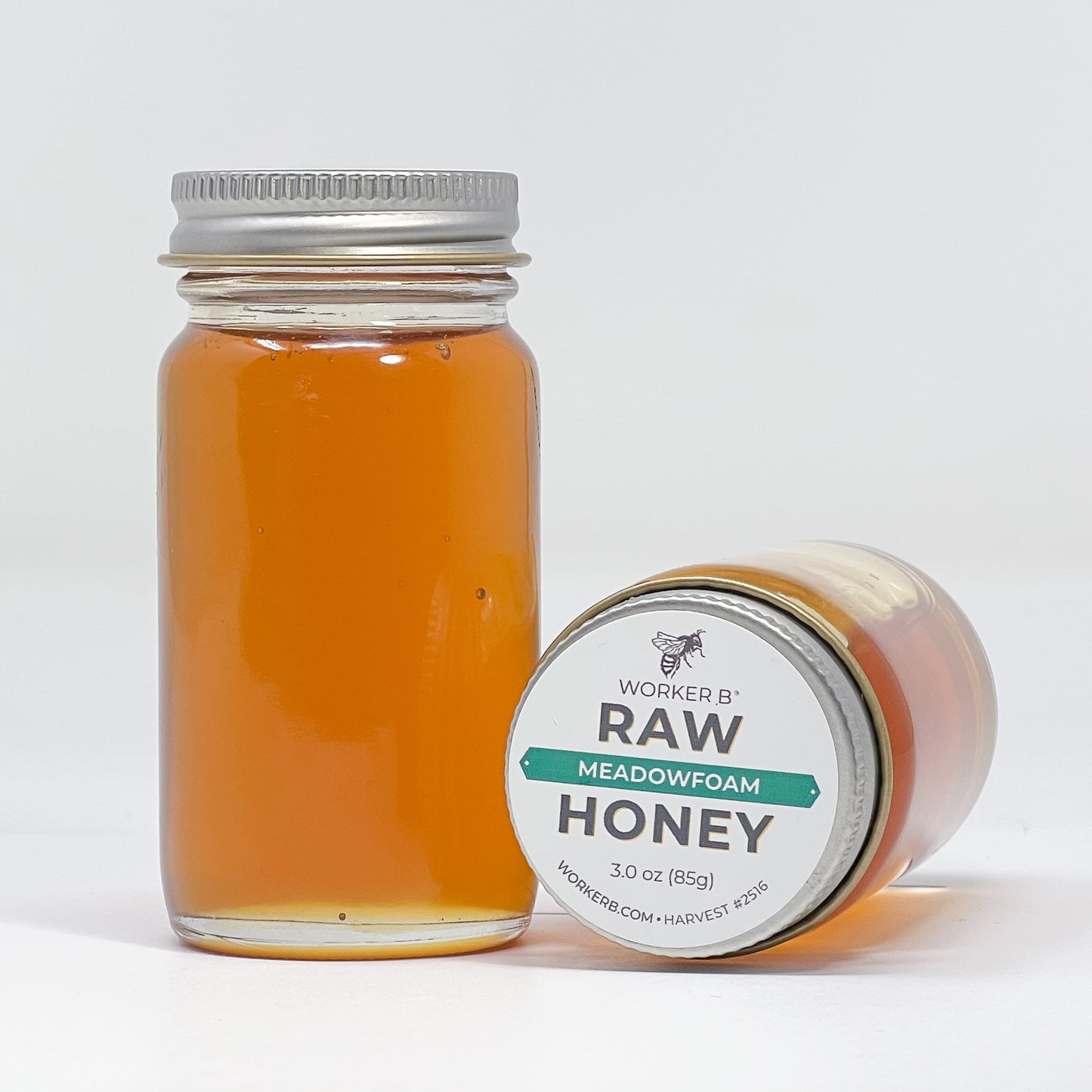 Jar of Worker B Raw Meadowfoam Honey with a white label on a light gray background