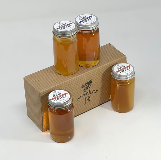 Four jars of raw honey on a wooden stand with 'Worker B' branding.