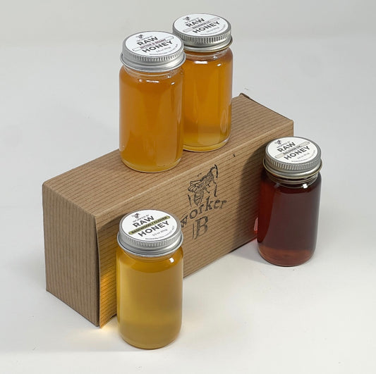 Four jars of raw honey on a wooden stand with 'Worker B' branding.