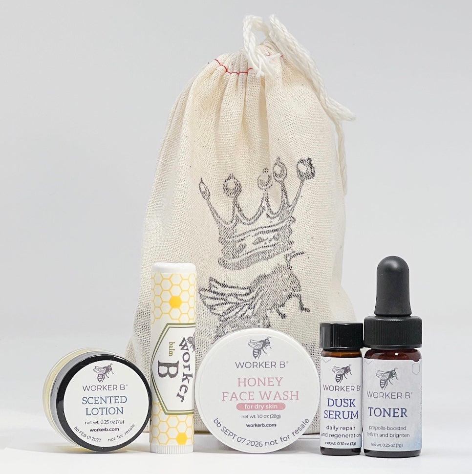 Set of Worker B skincare products including lotion, face wash, serum, and toner with a branded drawstring bag on a light gray background.