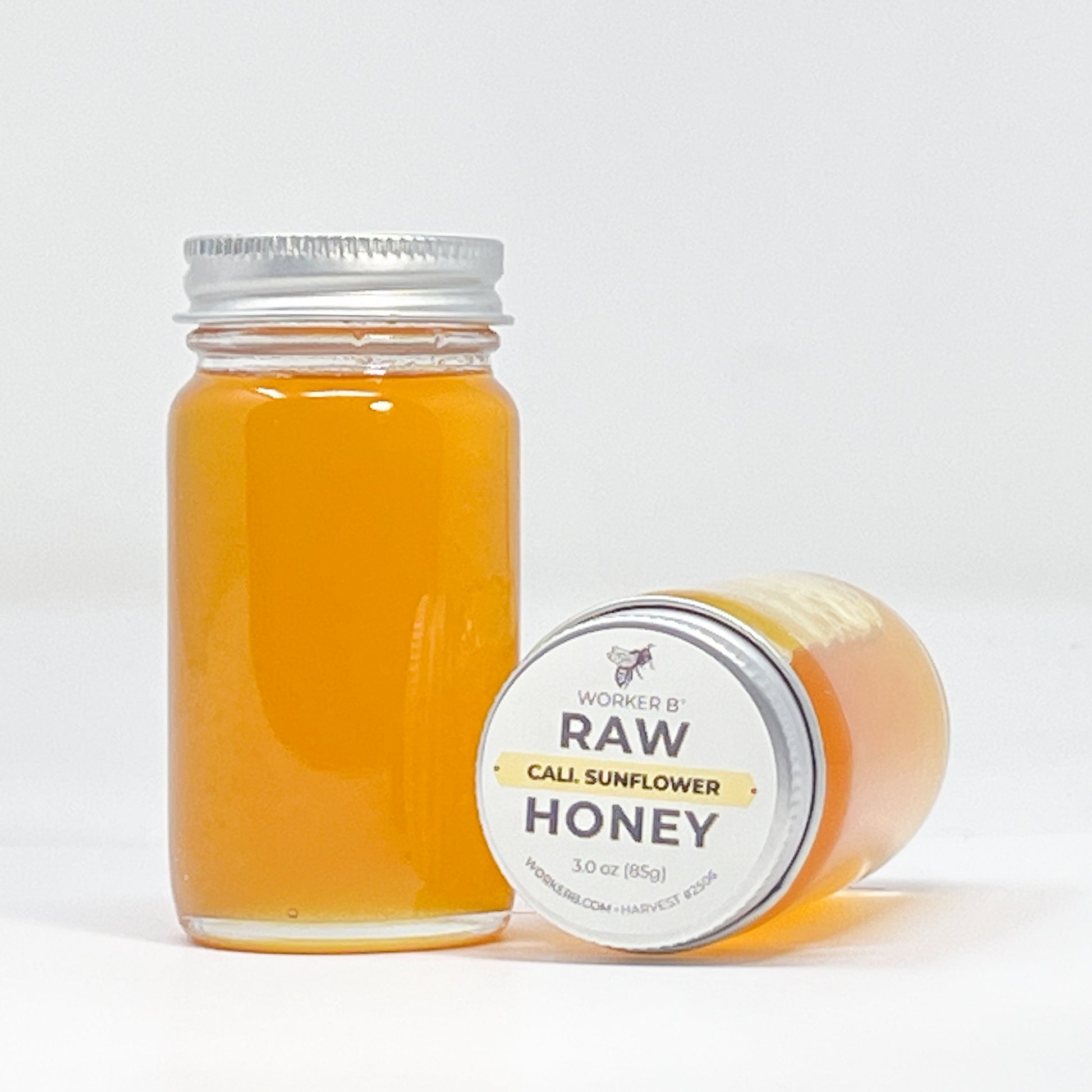 Jar of raw sunflower honey with a white label on a light gray background
