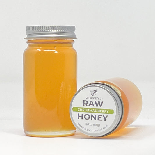 Jar of raw Christmas berry honey with a label on a white background