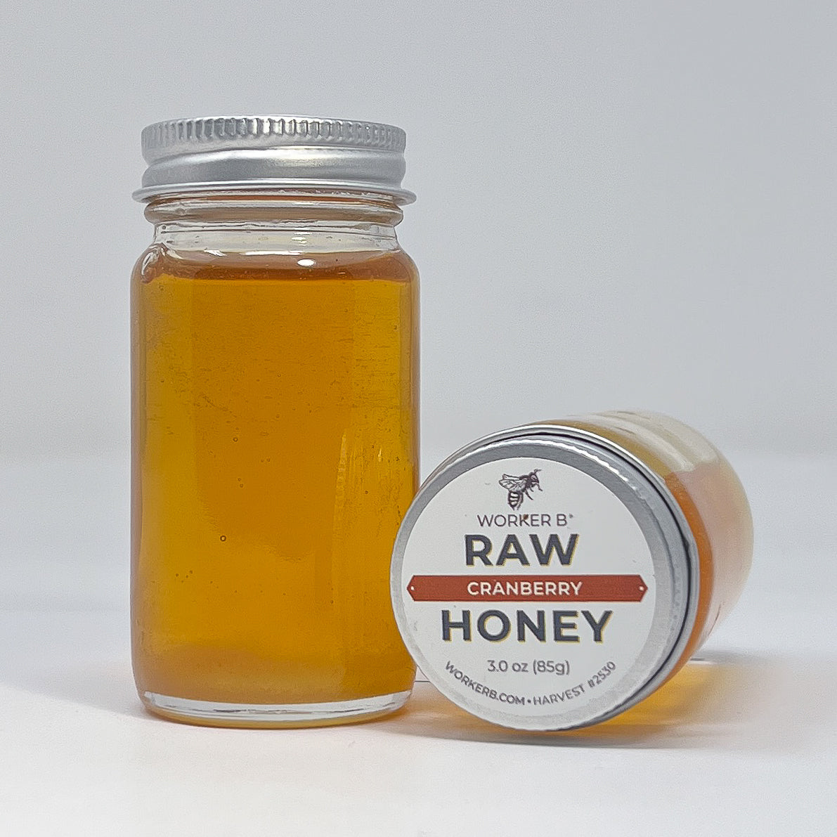 Jar of Worker B Raw Cranberry Honey with a white label on a light gray background