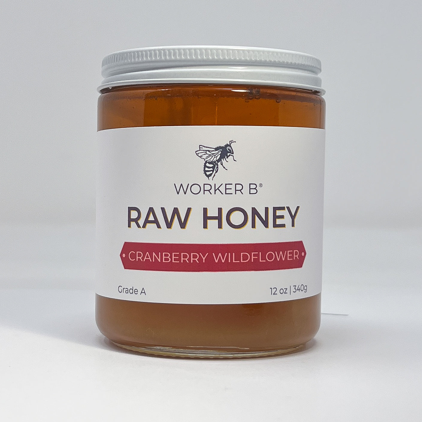 Jar of Worker B Raw Honey with cranberry wildflower flavor on a white background