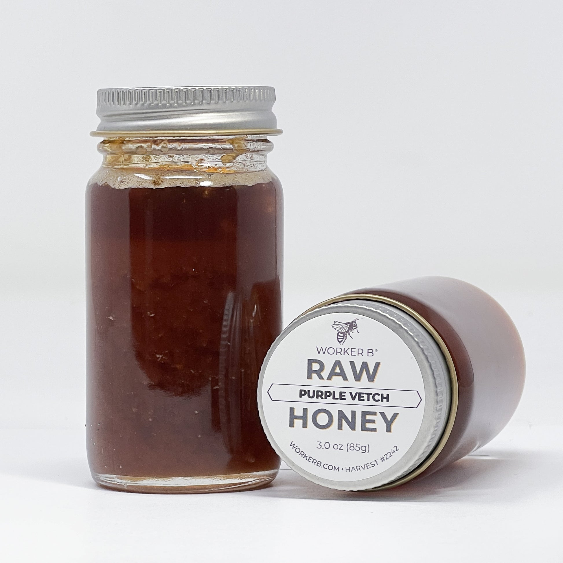 Jar of raw purple vetch honey with a label on a white background