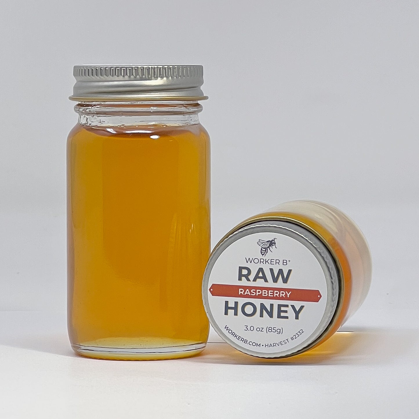 Jar of raw raspberry honey with a label on a white background